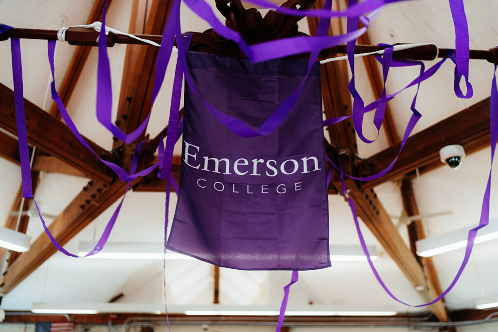 a purple Emerson College banner and purple streamers hang from rafters