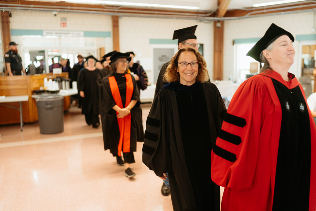 People in academic regalia walk in a line
