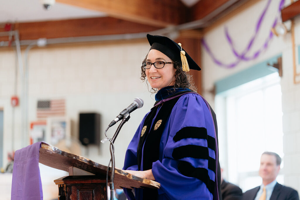 Woman in academic regalia speaks at podium