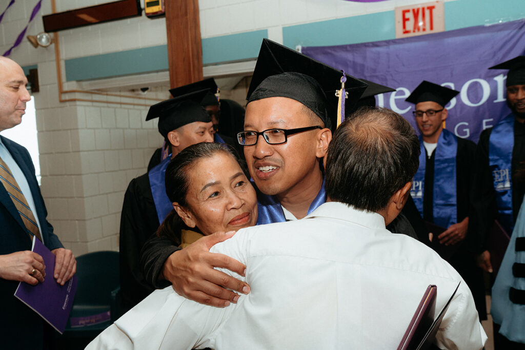 Man wearing mortarboard is hugged by a woman and a man