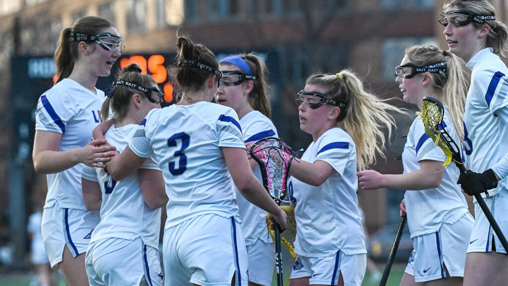 Women's lacrosse players gather in a celebration