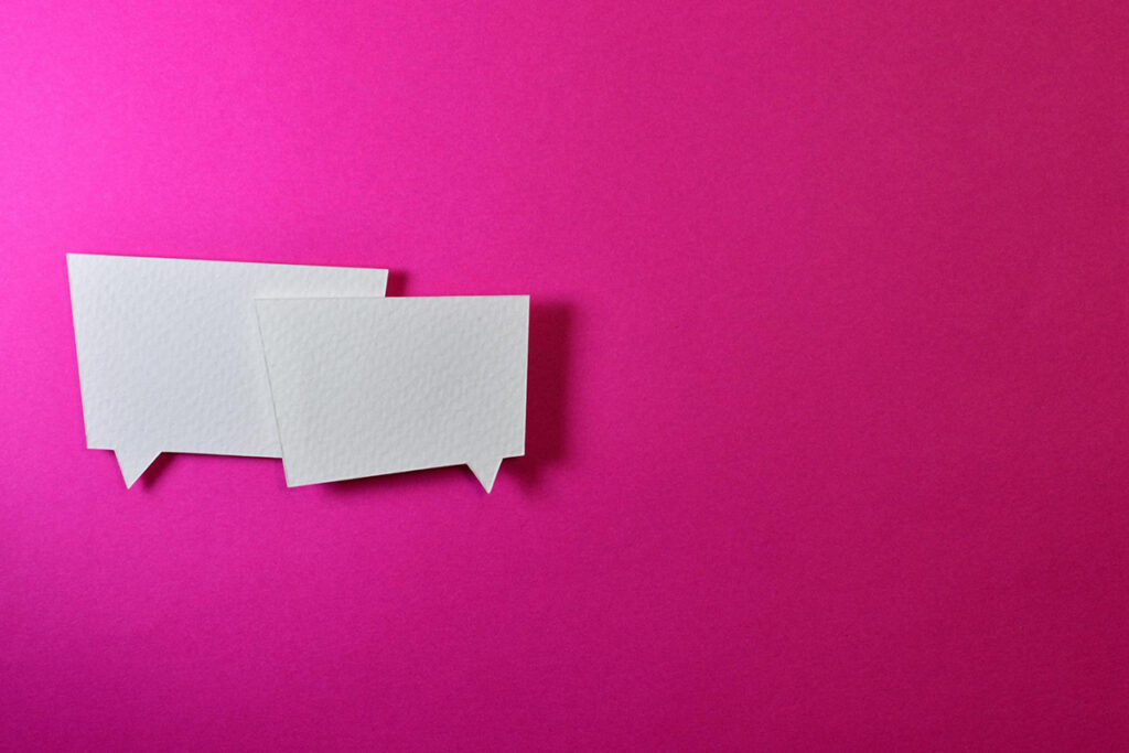 two white dialogue symbols overlapping against pink background