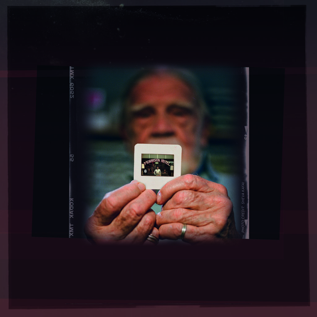 Henry Diltz holds up an image of Jim Morrison in front of the Morrison Hotel.