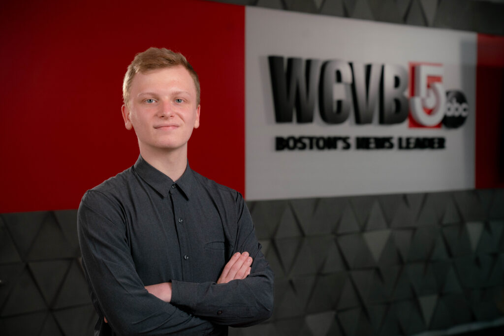 Aidan Vahey stands in front of a wall that says WCVB5