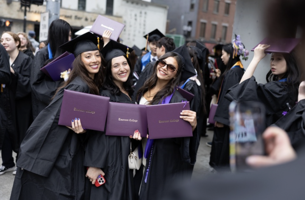 Three people pose for a photo with their diplomas