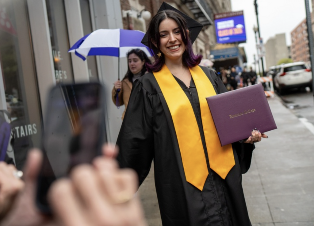 A graduate smiles while walking on the sidewalk