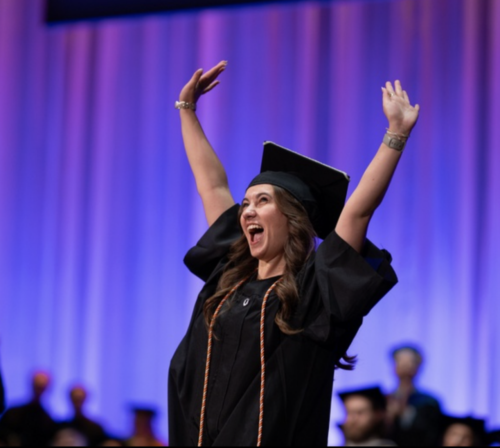 A person lifts their hands in the air on stage