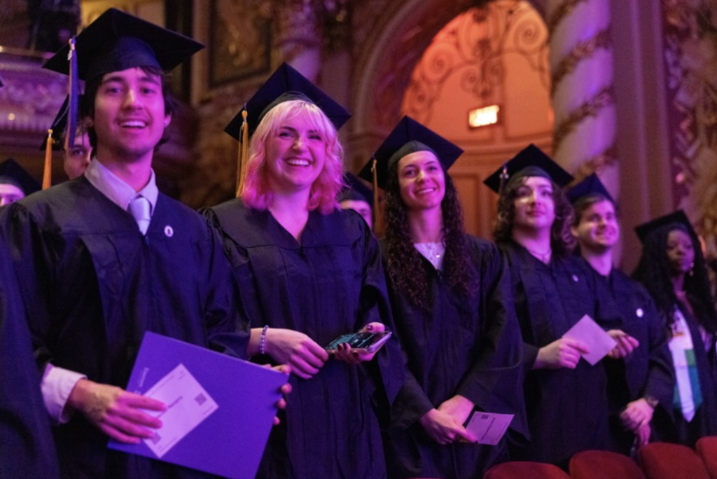 Several graduates stand in a row