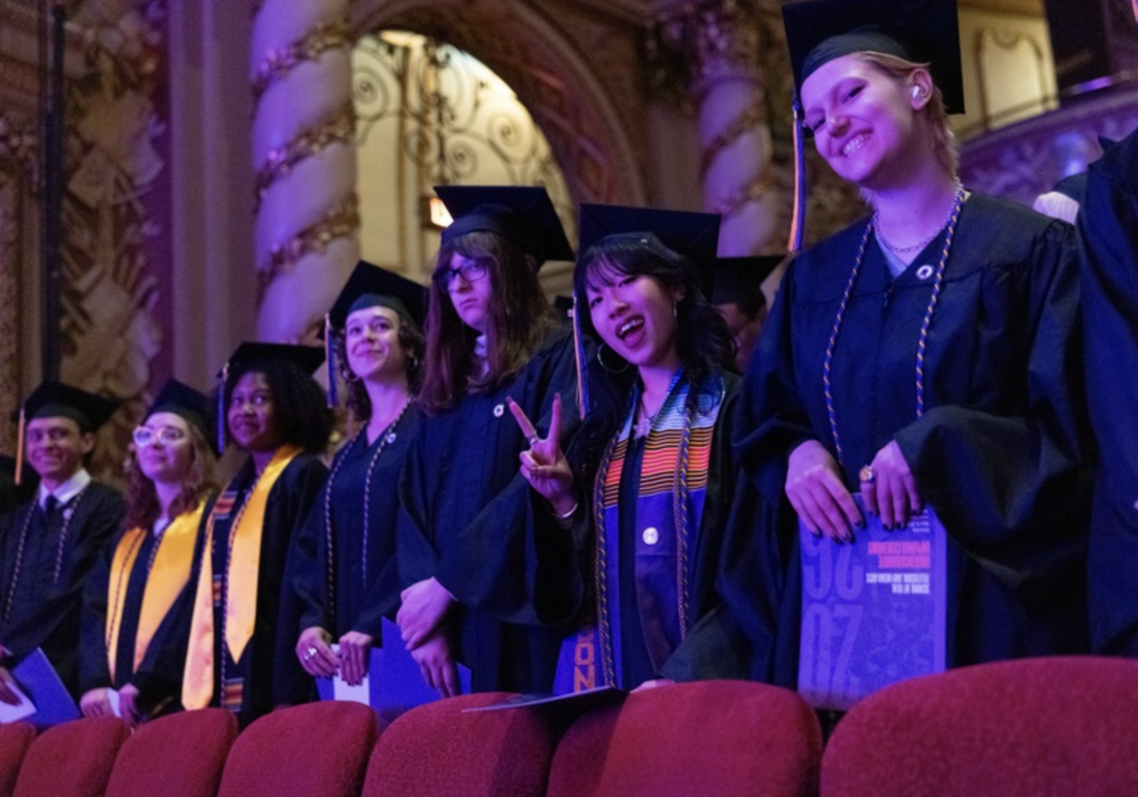 Several graduates stand in a row