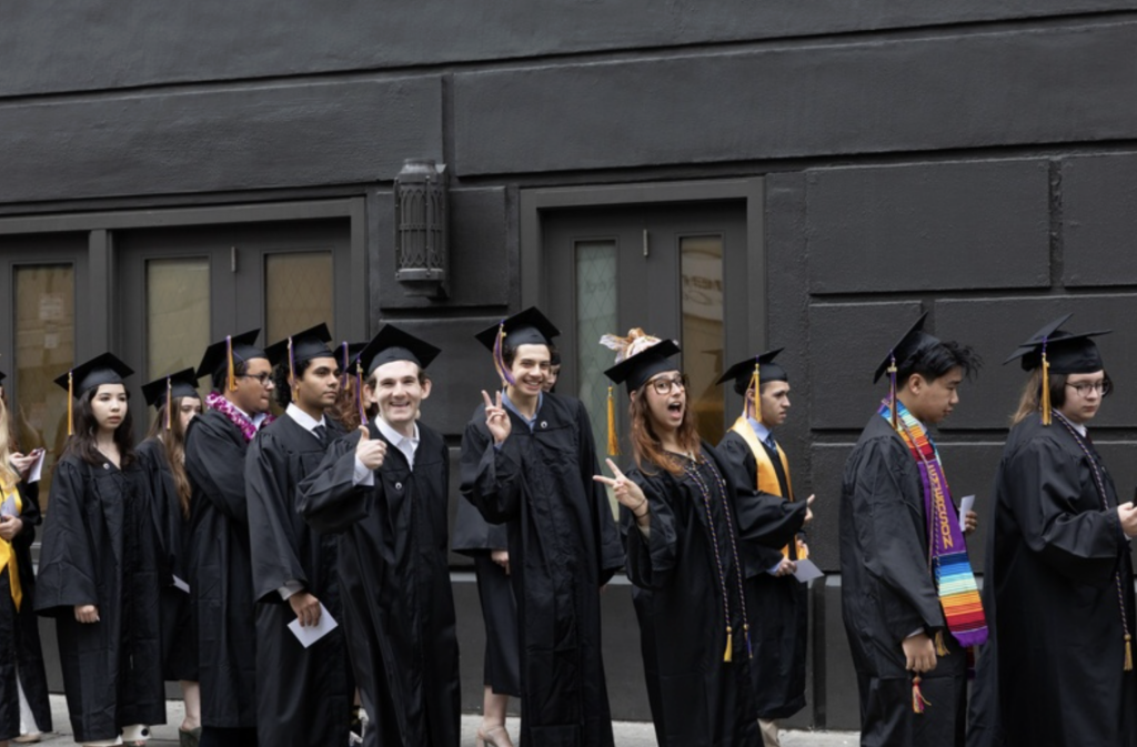 Several people give thumbs up while walking outside in line