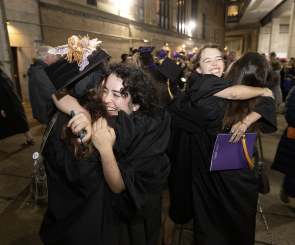 Students hug each other after graduating