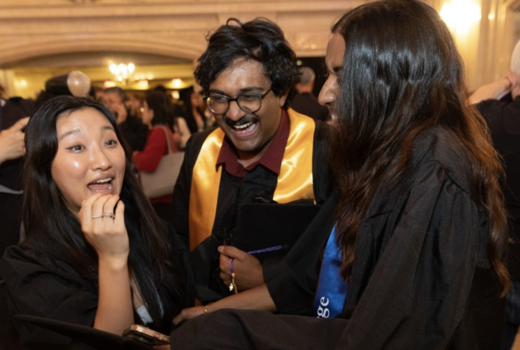Three students smile together after graduating