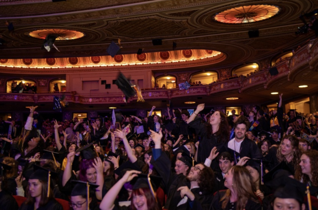 A sea of students throw their caps in the air