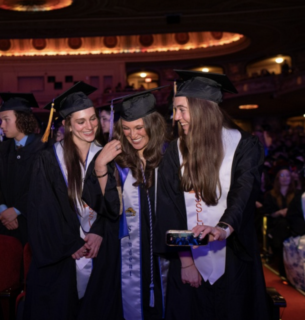 Three students smile and embrace each other