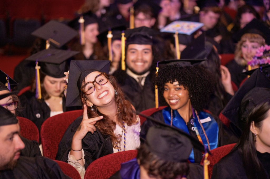 Three students smile for the camera while sitting