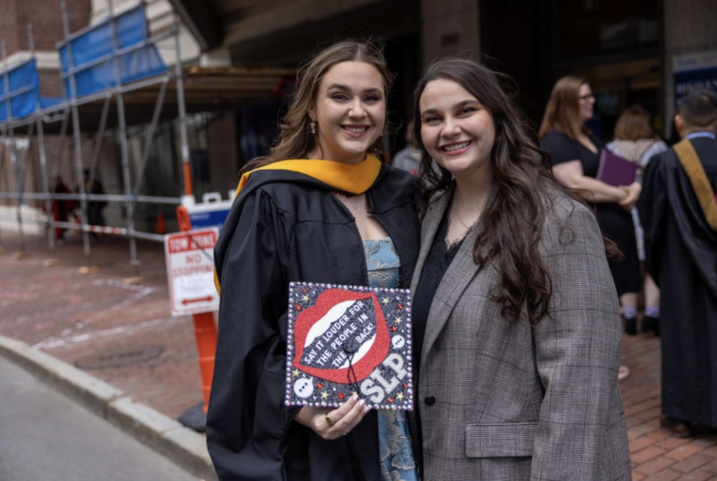 A graduate with another person smile for camera