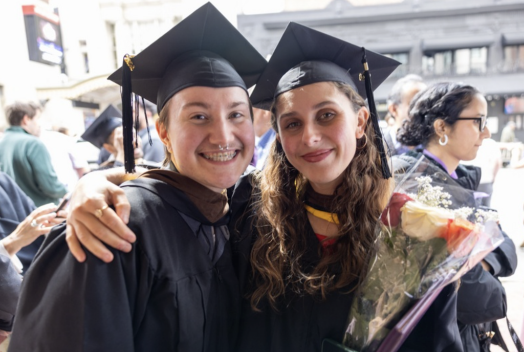 Two graduates smile for the camera