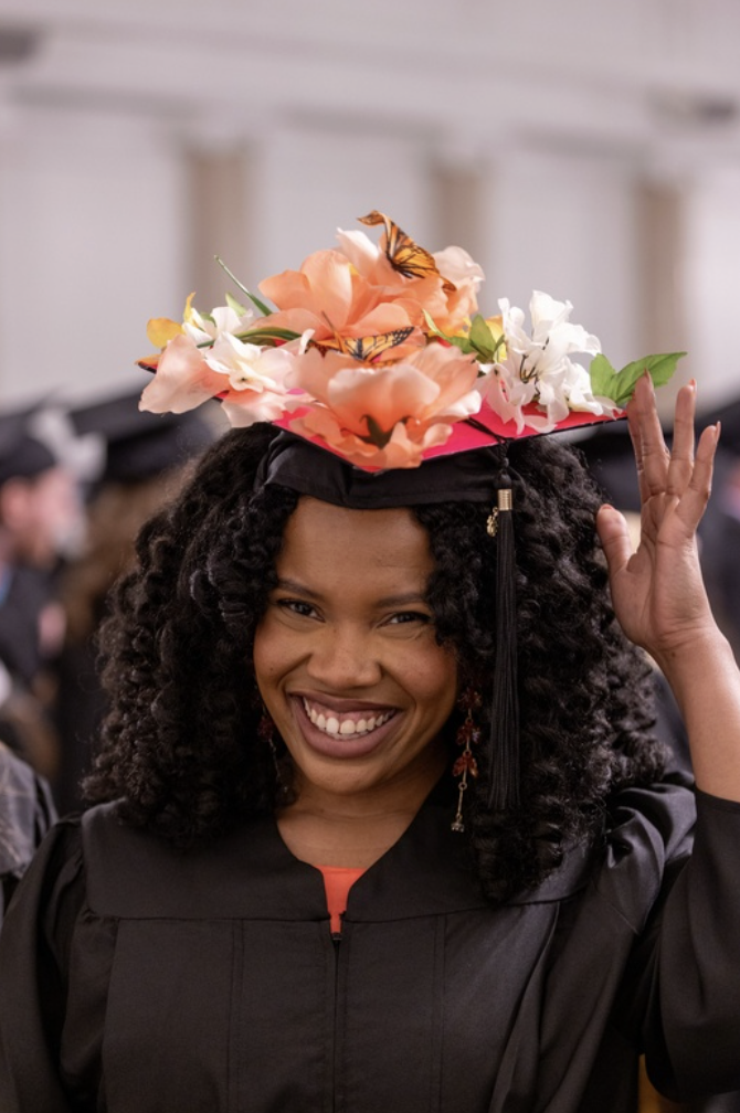 A graduate with a lot of flowers atop their cap