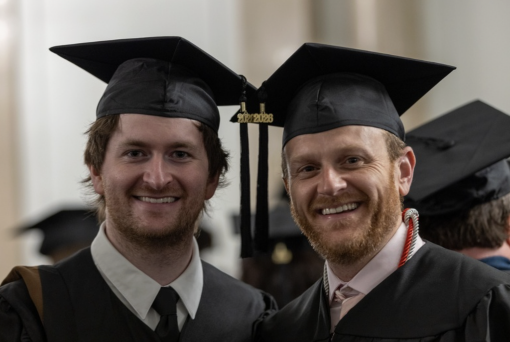 Two graduates smile