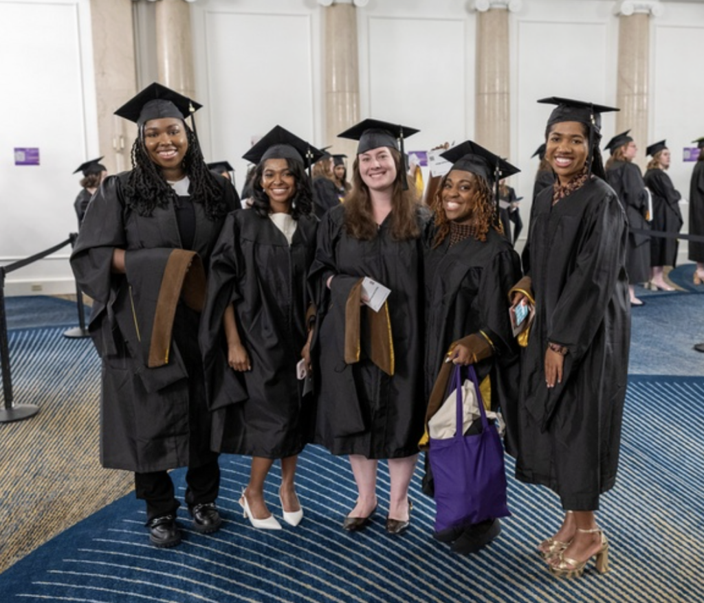 Five graduates in caps and gowns pose for photo